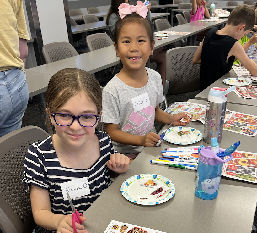 two students smiling at the camera during an activity 